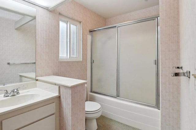 full bathroom featuring vanity, combined bath / shower with glass door, and toilet