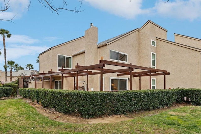 back of property featuring a yard and a pergola