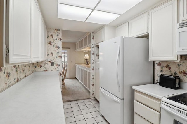 kitchen with white appliances, white cabinets, and light tile patterned flooring