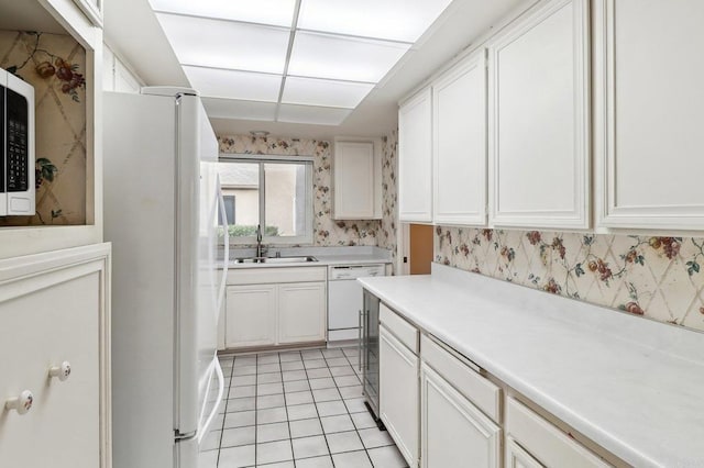 kitchen featuring white cabinetry, sink, light tile patterned flooring, and white appliances