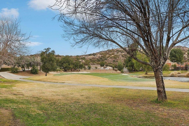 view of community featuring view of golf course and a yard