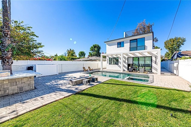 rear view of property with a balcony, a yard, a pool with hot tub, and a patio