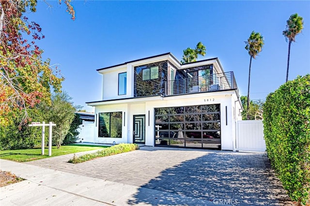 view of front facade with a garage, a balcony, and a front lawn