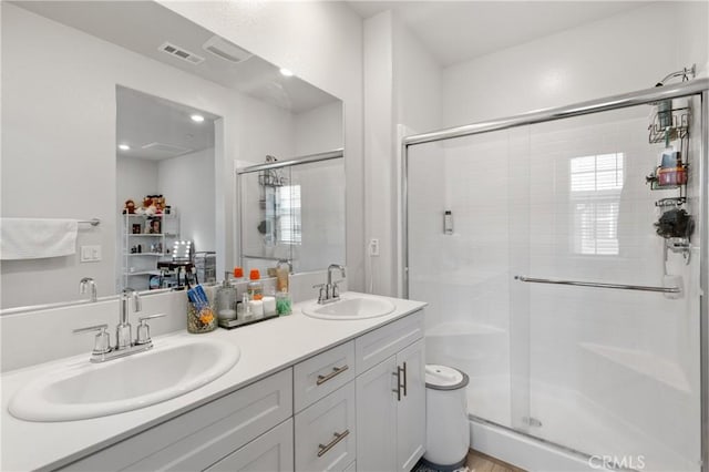 full bathroom featuring double vanity, a stall shower, a sink, and visible vents