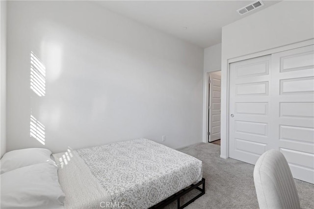 bedroom featuring a closet, visible vents, and light carpet