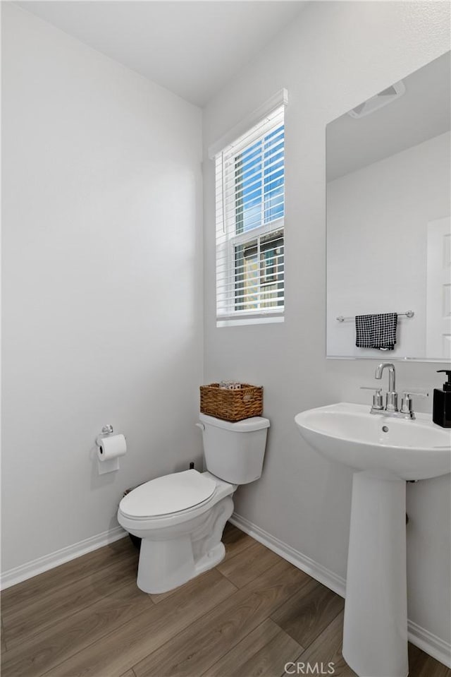 bathroom featuring toilet, a sink, baseboards, and wood finished floors