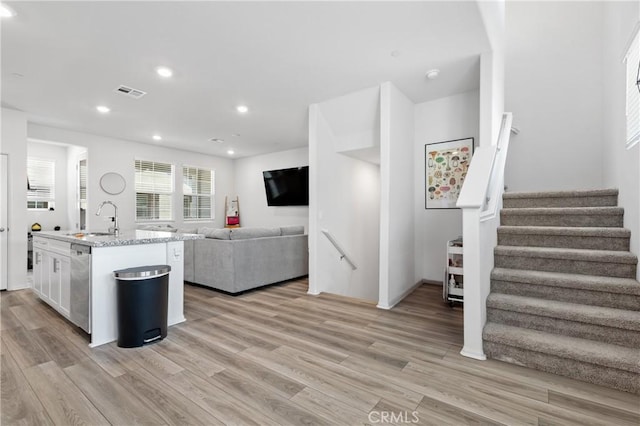 kitchen featuring visible vents, open floor plan, a sink, white cabinetry, and stainless steel dishwasher