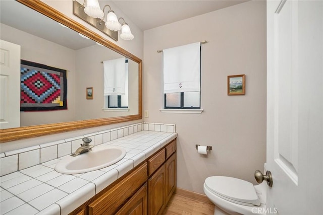 bathroom featuring vanity, baseboards, toilet, and wood finished floors