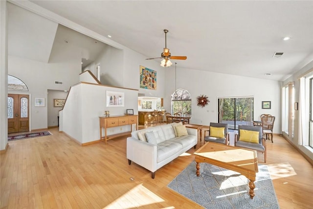 living room with a ceiling fan, high vaulted ceiling, visible vents, and light wood-style flooring