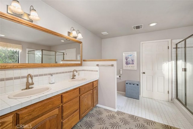 full bathroom featuring double vanity, visible vents, a sink, and a stall shower
