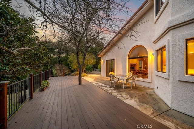 deck at dusk featuring outdoor dining space