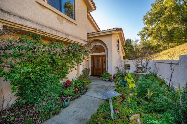property entrance featuring fence, french doors, and stucco siding