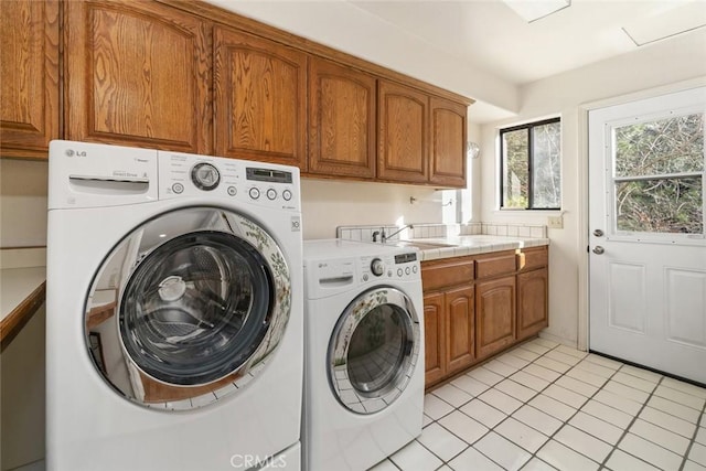 laundry room with light tile patterned floors, a sink, cabinet space, and washing machine and clothes dryer