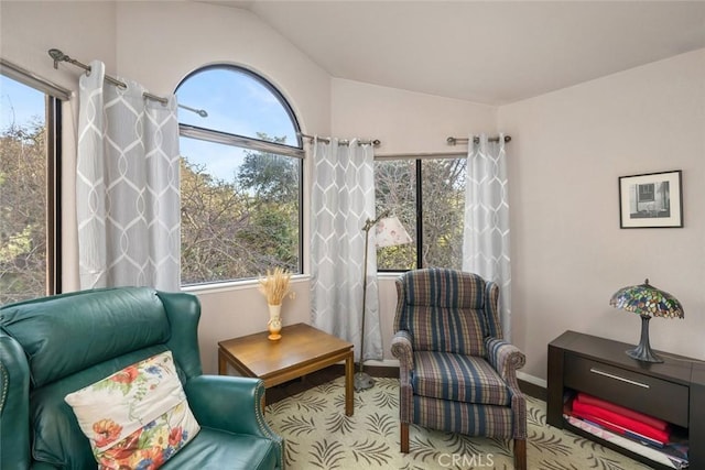 sitting room featuring baseboards, plenty of natural light, and lofted ceiling