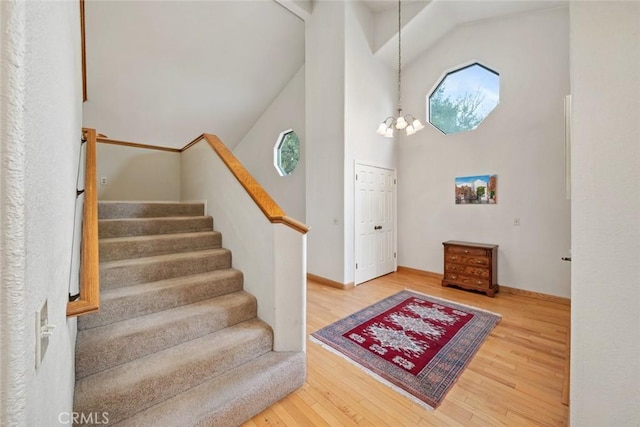 foyer with high vaulted ceiling, plenty of natural light, wood finished floors, and stairway