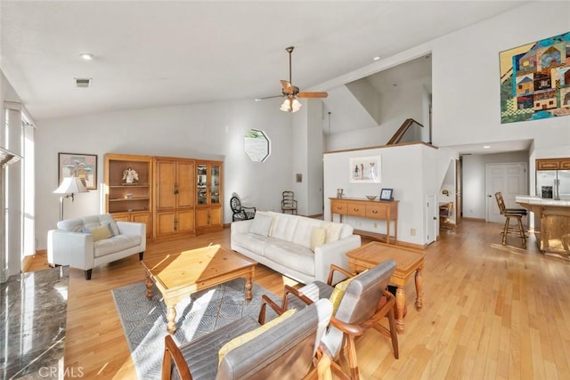 living room featuring high vaulted ceiling, visible vents, ceiling fan, and light wood-style floors