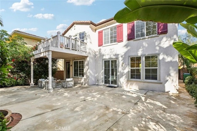 rear view of property featuring a balcony and a patio