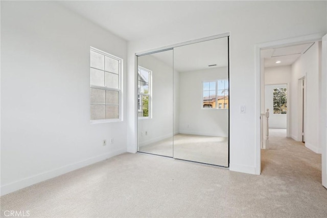 unfurnished bedroom with light colored carpet and a closet