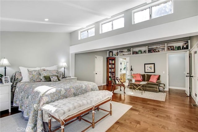 bedroom featuring hardwood / wood-style flooring and a towering ceiling