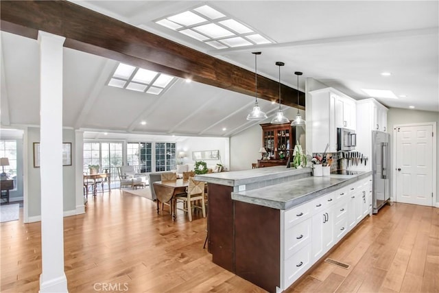 kitchen with lofted ceiling with beams, white cabinetry, hanging light fixtures, kitchen peninsula, and light hardwood / wood-style flooring