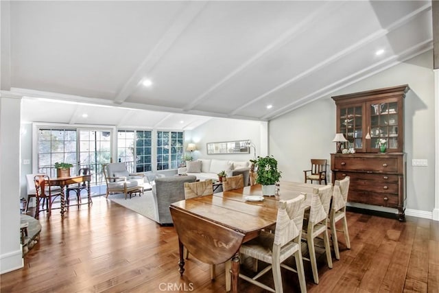 dining space with wood-type flooring and lofted ceiling with beams