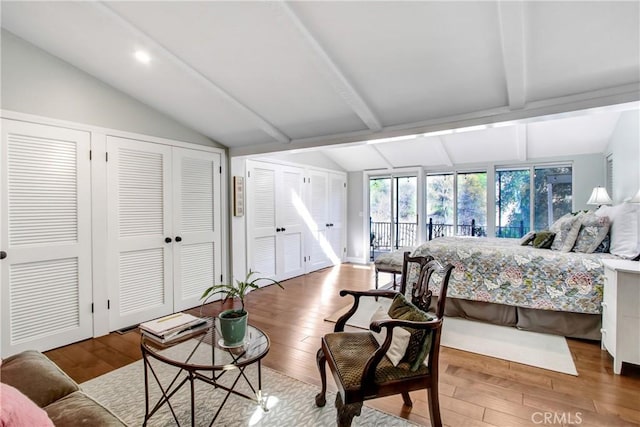 bedroom with two closets, wood-type flooring, and vaulted ceiling with beams