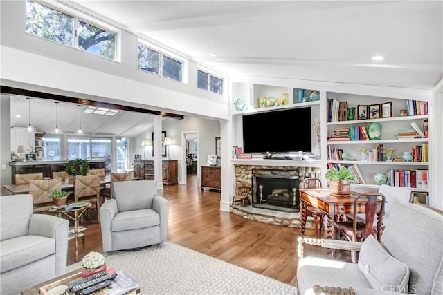 living room with lofted ceiling with beams, hardwood / wood-style floors, a fireplace, and built in shelves