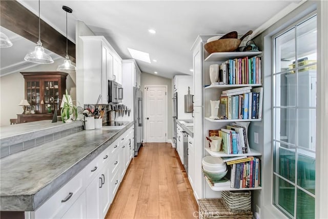 kitchen featuring white cabinetry, decorative light fixtures, lofted ceiling, and light wood-type flooring