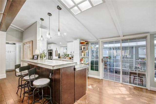 kitchen featuring pendant lighting, vaulted ceiling with beams, oven, and white cabinets