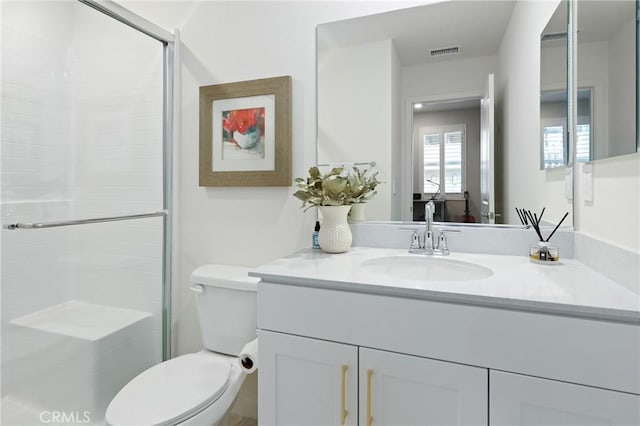 bathroom with vanity, toilet, and a shower with door