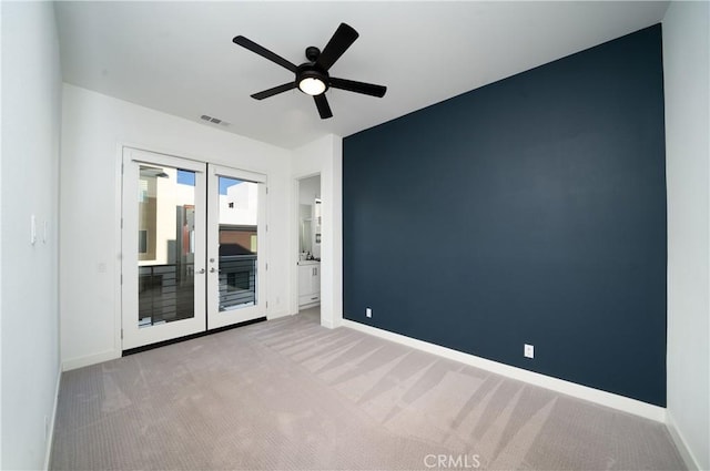 empty room with french doors, light colored carpet, and ceiling fan