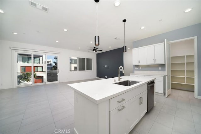 kitchen featuring pendant lighting, sink, white cabinets, stainless steel dishwasher, and a center island with sink