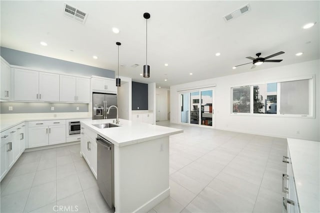 kitchen with sink, an island with sink, white cabinets, and appliances with stainless steel finishes