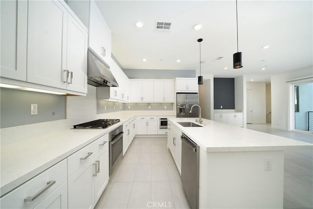 kitchen with appliances with stainless steel finishes, white cabinetry, an island with sink, sink, and hanging light fixtures