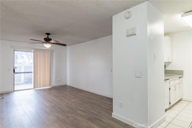 unfurnished room with ceiling fan, light hardwood / wood-style flooring, and a textured ceiling