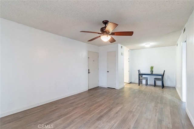 empty room featuring ceiling fan, a textured ceiling, and light hardwood / wood-style floors