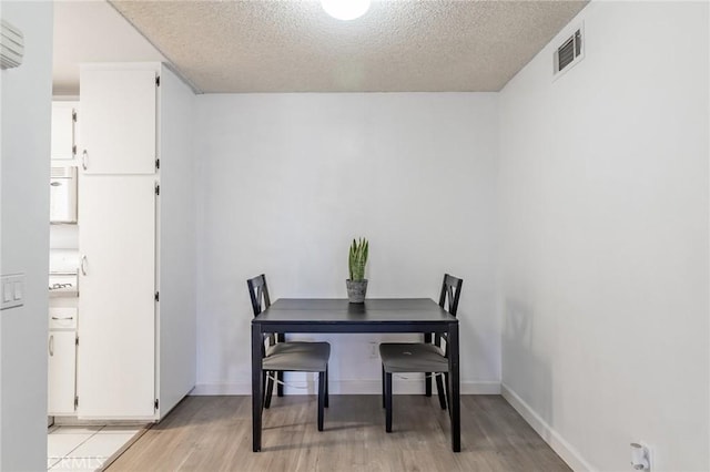 dining area with a textured ceiling and light hardwood / wood-style flooring