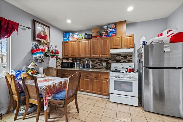 kitchen with dark stone countertops, stainless steel fridge, gas range gas stove, and tasteful backsplash