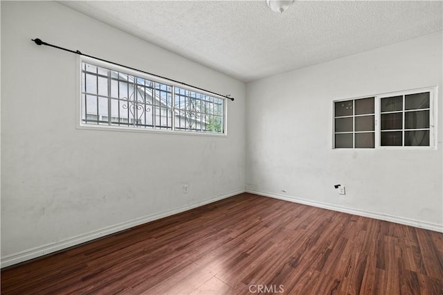 spare room featuring wood-type flooring and a textured ceiling