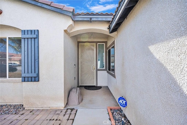 property entrance featuring a tile roof and stucco siding