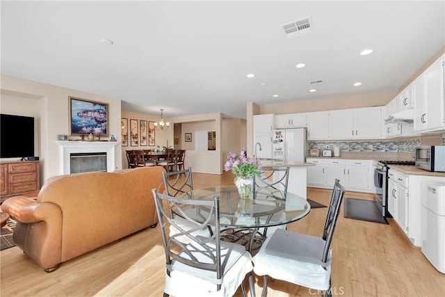 dining room featuring light wood-style floors, recessed lighting, a chandelier, and visible vents