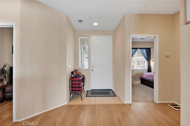 foyer entrance with wood finished floors, visible vents, and baseboards