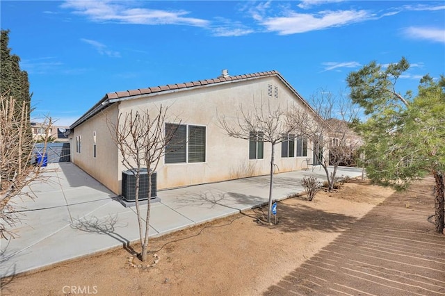 back of property with a patio area, a tile roof, central AC, and stucco siding