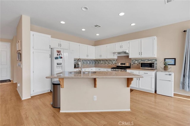 kitchen featuring stainless steel appliances, visible vents, white cabinetry, a sink, and under cabinet range hood