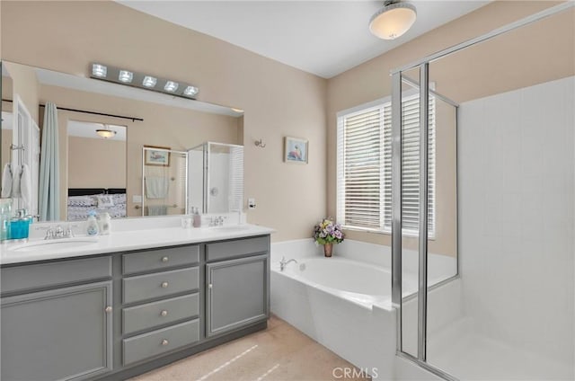 bathroom with a garden tub, double vanity, a stall shower, and a sink