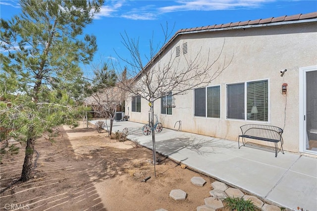 back of house featuring a patio area, central AC, and stucco siding