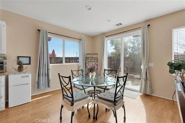 dining room featuring light wood-style floors, baseboards, and visible vents