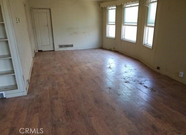 empty room with dark hardwood / wood-style floors and built in features