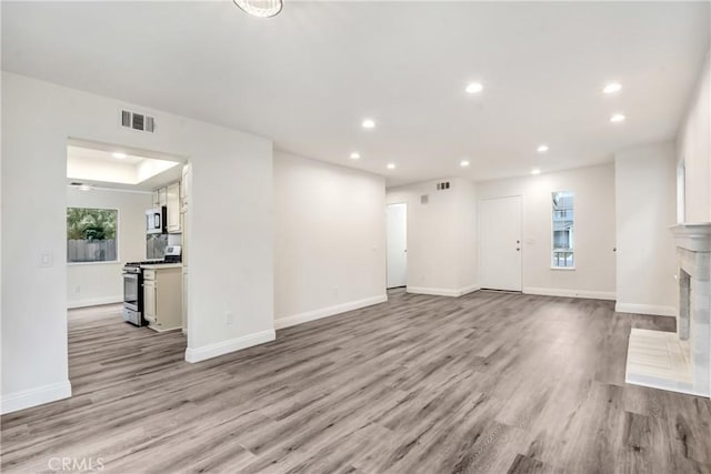 unfurnished living room featuring a tray ceiling and light hardwood / wood-style floors