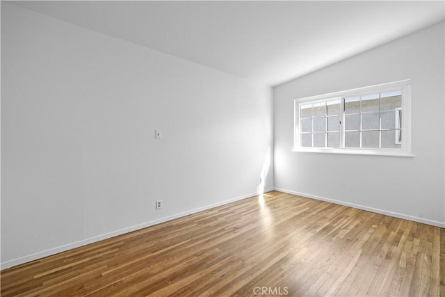 unfurnished room with lofted ceiling and hardwood / wood-style flooring